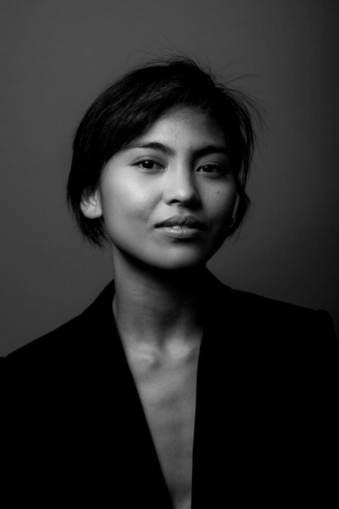 Black and white portrait photo of Marie Lloyd Paspe. They are facing the camera wearing a black sportscoat.