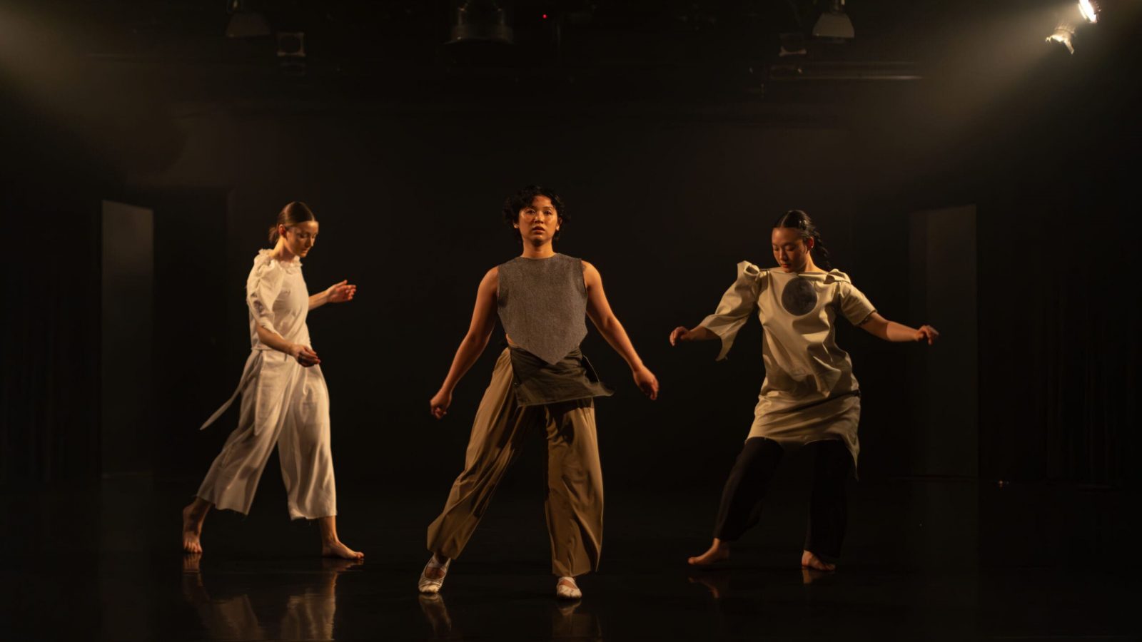 three dancers caught in swinging movement.