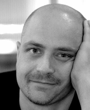 Black and white headshot of Peter Nigrini. They look into the camera with their head resting on their hand.