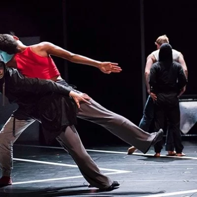 Dancers on a spotlight stage perform dyanmic full body movements