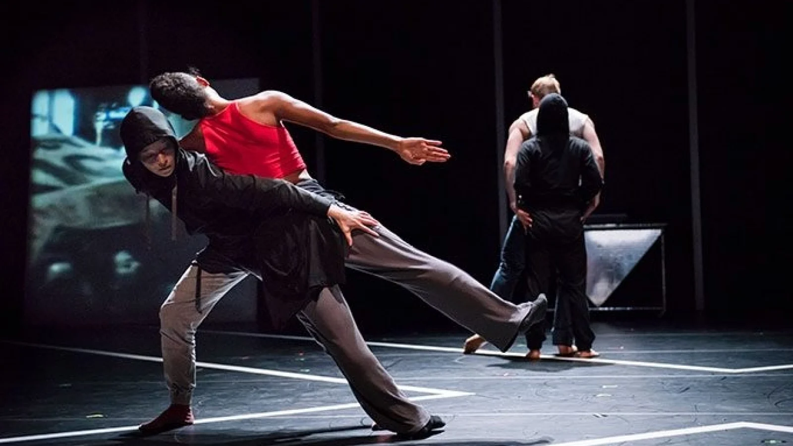 Dancers on a spotlight stage perform dyanmic full body movements