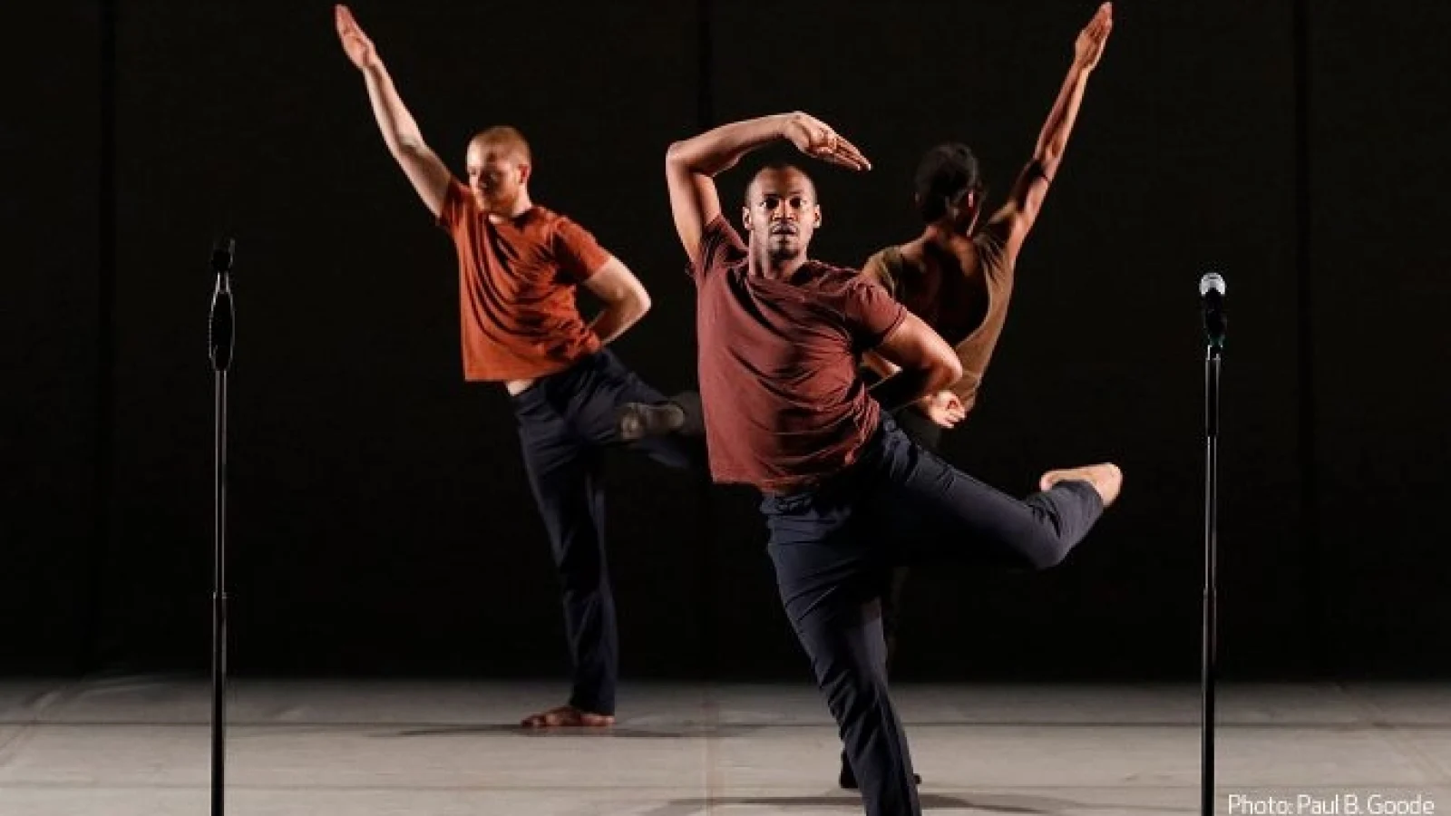 Dancers strike dynamic angular poses in front of a black background