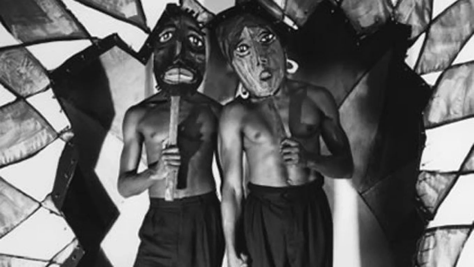 Black and white photos of shirtless dancers holding large masks in front of their faces